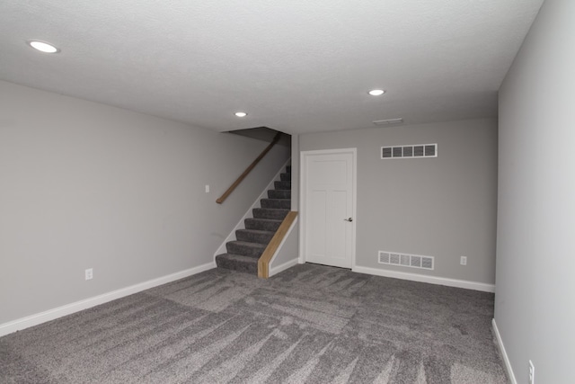 basement with a textured ceiling and dark colored carpet