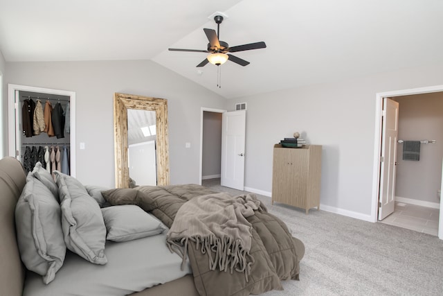 bedroom with a spacious closet, ensuite bath, a closet, ceiling fan, and vaulted ceiling