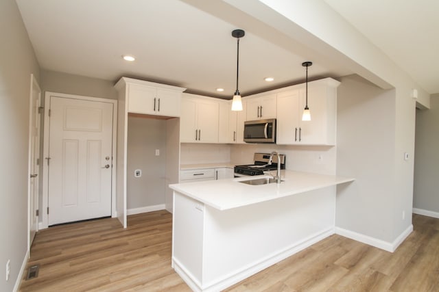 kitchen featuring light hardwood / wood-style floors, kitchen peninsula, appliances with stainless steel finishes, white cabinets, and hanging light fixtures