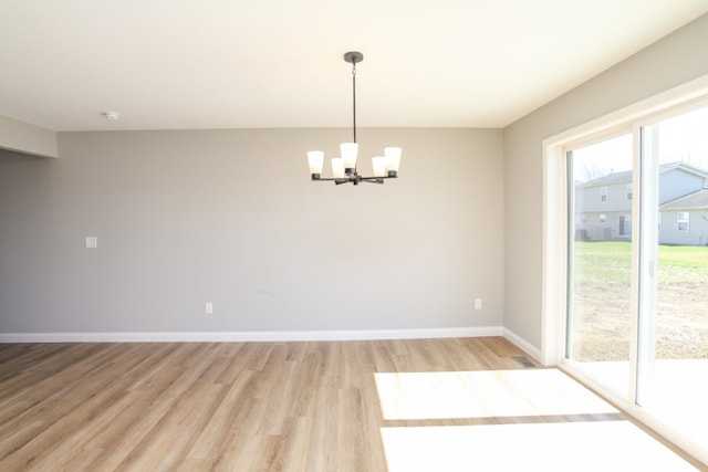 spare room with light hardwood / wood-style flooring and an inviting chandelier