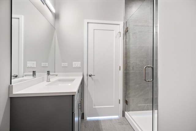 bathroom with a shower with door, large vanity, and hardwood / wood-style flooring