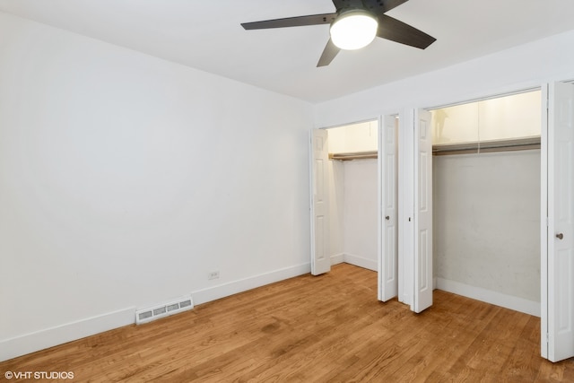 unfurnished bedroom with ceiling fan, multiple closets, and light hardwood / wood-style floors