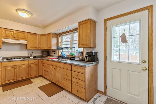 kitchen with a sink, light tile patterned flooring, white gas stovetop, and under cabinet range hood