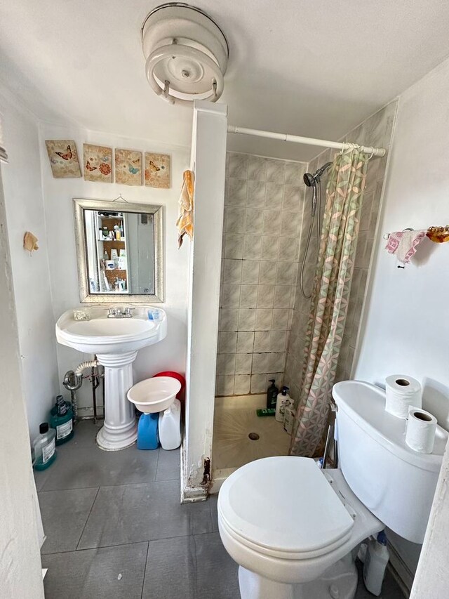 bathroom featuring toilet, tile floors, and a shower with curtain