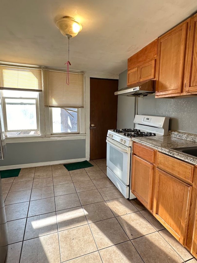 kitchen with light tile floors, white range with gas stovetop, and sink