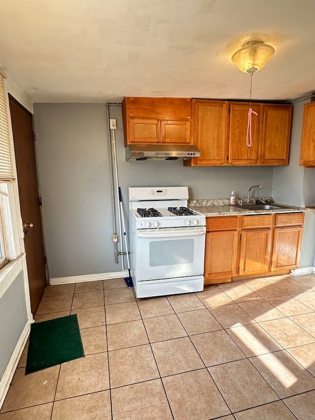 kitchen featuring white range with gas stovetop, sink, and light tile flooring