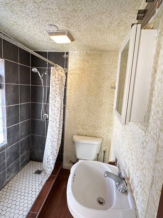 bathroom with a textured ceiling, toilet, walk in shower, and sink