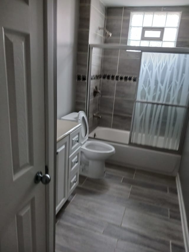 full bathroom with hardwood / wood-style floors, tiled shower / bath combo, vanity, and toilet