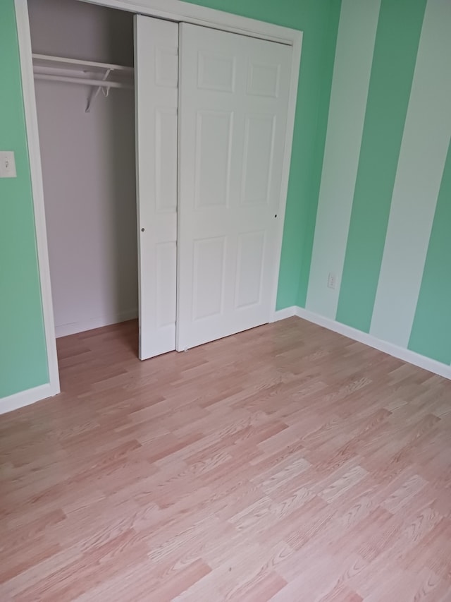 unfurnished bedroom featuring light wood-type flooring and a closet