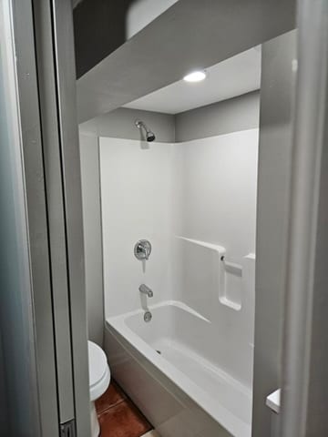 bathroom featuring toilet, washtub / shower combination, and tile floors