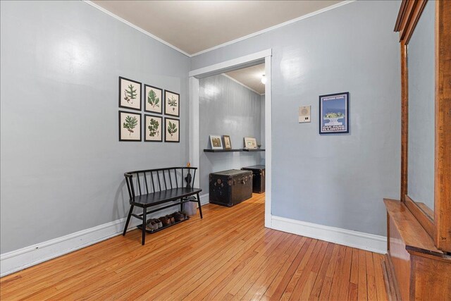 sitting room with crown molding and light wood-type flooring