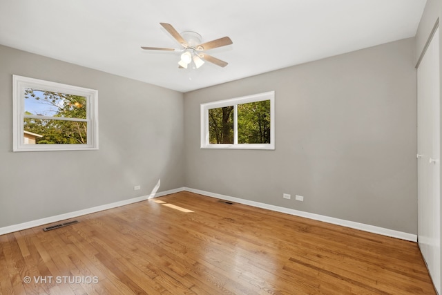 empty room featuring a wealth of natural light, light hardwood / wood-style floors, and ceiling fan