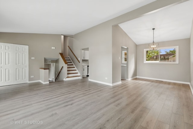 unfurnished living room featuring light hardwood / wood-style floors, an inviting chandelier, and vaulted ceiling