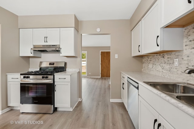 kitchen with decorative backsplash, light hardwood / wood-style flooring, stainless steel appliances, sink, and white cabinets