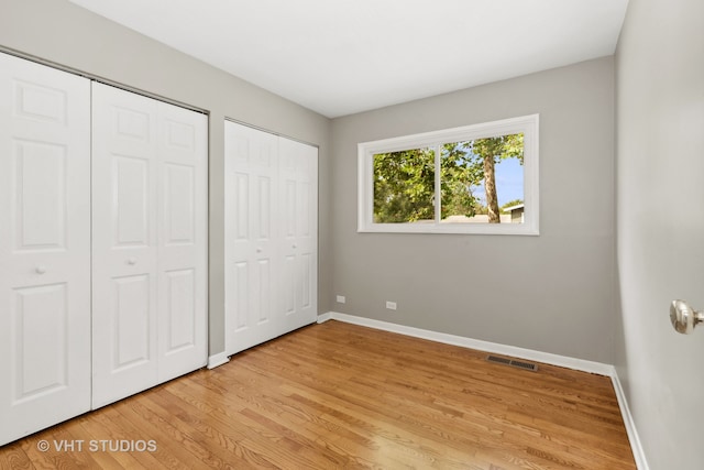 unfurnished bedroom featuring light hardwood / wood-style flooring and multiple closets