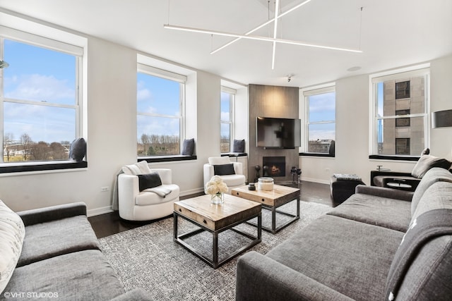 living room with dark hardwood / wood-style flooring, a large fireplace, and a healthy amount of sunlight