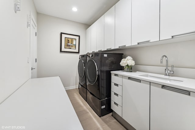 laundry area featuring washing machine and dryer, light hardwood / wood-style flooring, cabinets, and sink