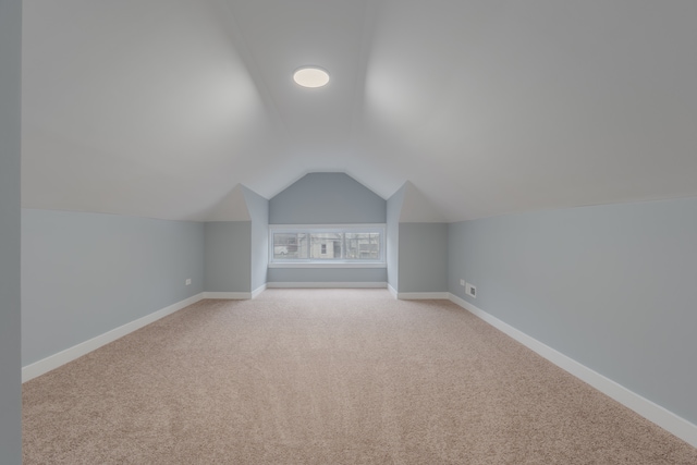 bonus room with light carpet and vaulted ceiling