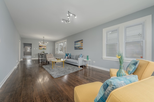 living room with dark wood-type flooring, track lighting, and a chandelier