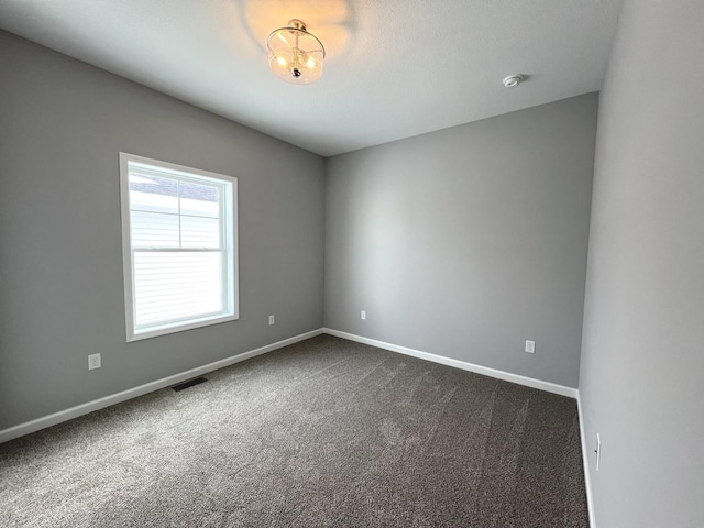 spare room with dark colored carpet