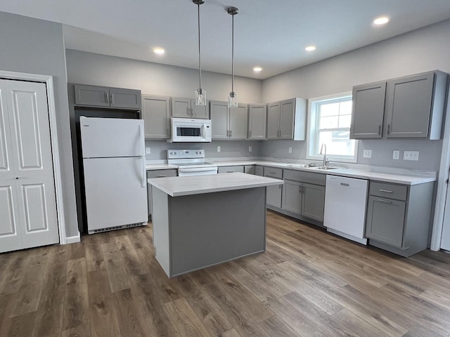 kitchen with white appliances, gray cabinets, a kitchen island, sink, and decorative light fixtures