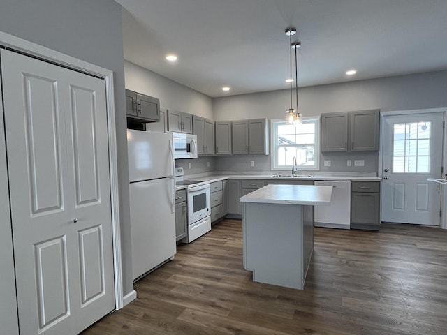 kitchen with white appliances, dark wood-type flooring, pendant lighting, a kitchen island, and gray cabinetry