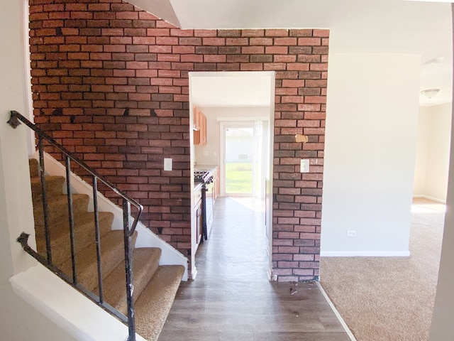 foyer with hardwood / wood-style flooring and brick wall