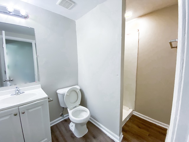 bathroom featuring walk in shower, wood-type flooring, vanity, and toilet