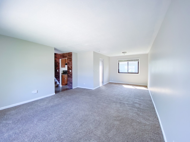 unfurnished living room featuring brick wall and carpet