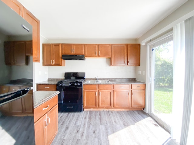 kitchen featuring sink, light hardwood / wood-style floors, and black gas range oven