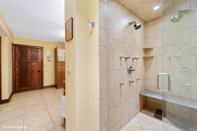 bathroom with a shower with shower door and tile flooring