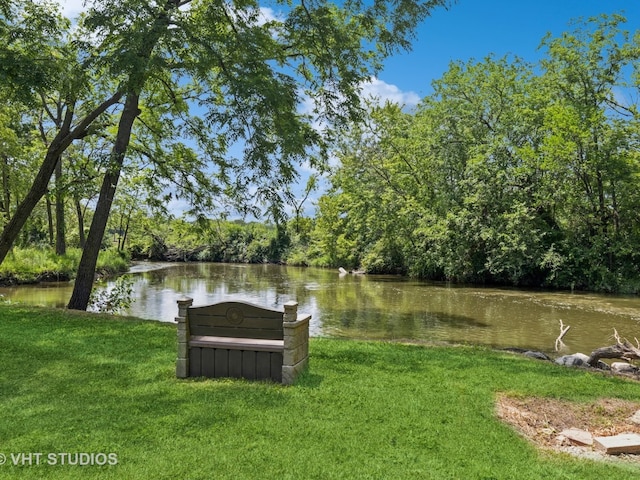 exterior space with a water view, a wooded view, and a lawn