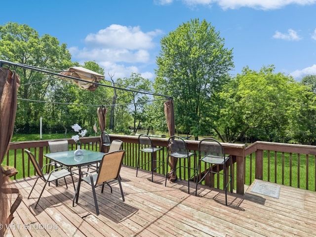 wooden terrace with outdoor dining area and a lawn