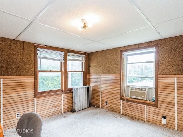 empty room featuring radiator heating unit, cooling unit, a paneled ceiling, and carpet flooring