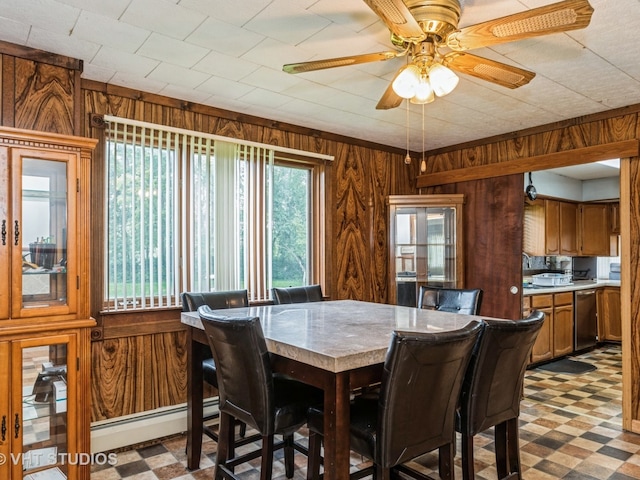 dining space with a baseboard heating unit, ceiling fan, and wooden walls