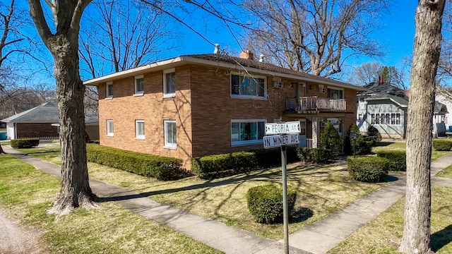 view of front of property featuring a balcony and a front lawn