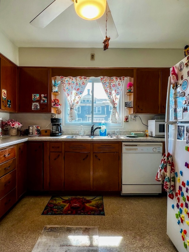 kitchen with a skylight, light colored carpet, white appliances, and sink