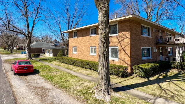 view of home's exterior with a balcony and a yard