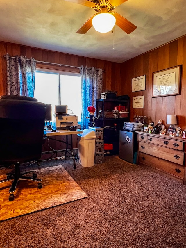 office space featuring ceiling fan, dark carpet, and wood walls