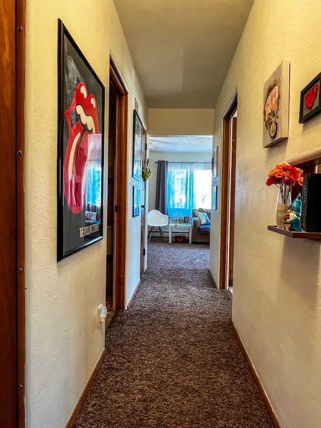 hall with dark colored carpet