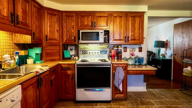 kitchen with sink, white appliances, dark tile floors, and tasteful backsplash