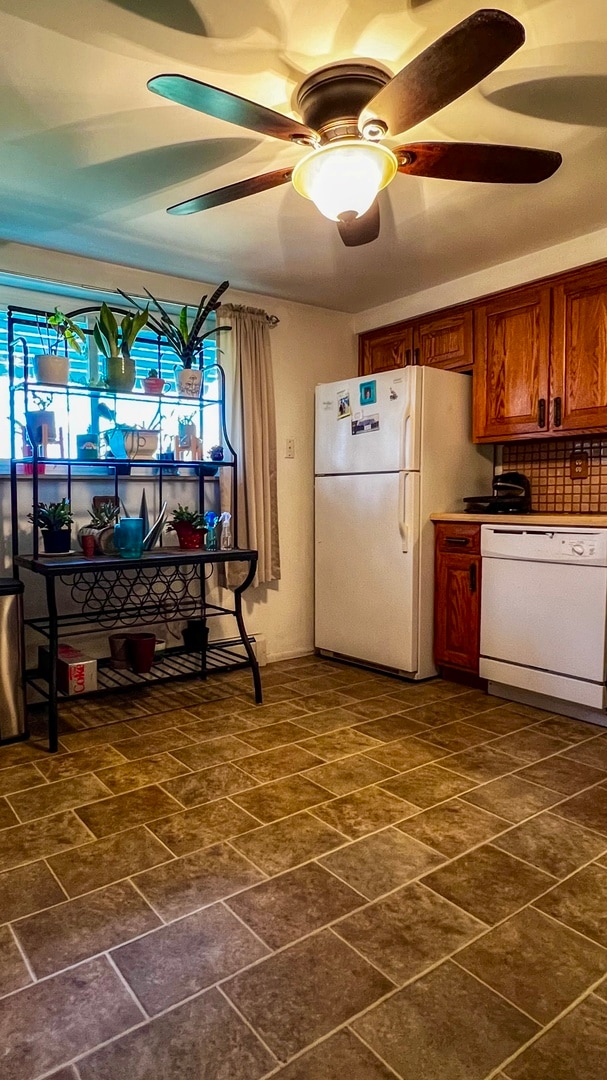 kitchen with backsplash, dark tile flooring, ceiling fan, and white appliances