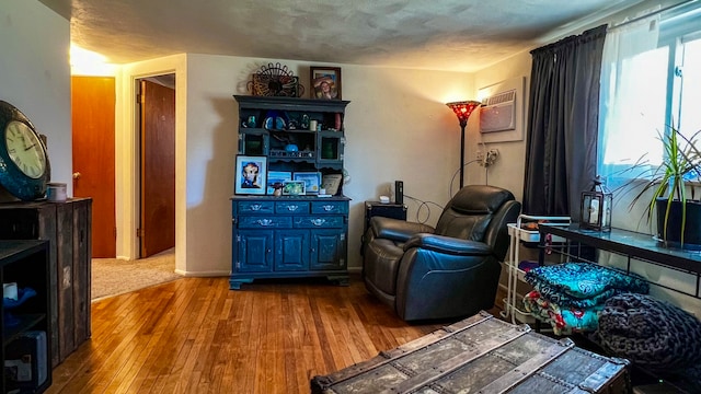 sitting room with light hardwood / wood-style flooring and a wall unit AC