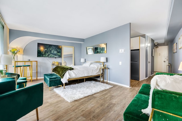 bedroom featuring stainless steel refrigerator and light hardwood / wood-style flooring