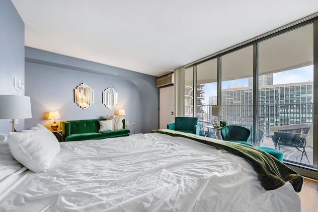 bedroom with a baseboard heating unit, a wall mounted AC, floor to ceiling windows, wood-type flooring, and access to outside