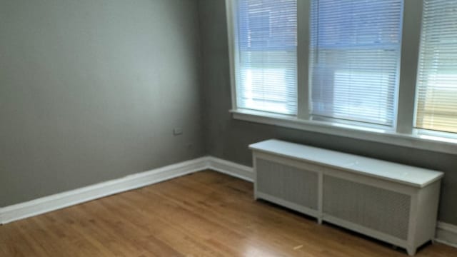 empty room with radiator heating unit and hardwood / wood-style flooring