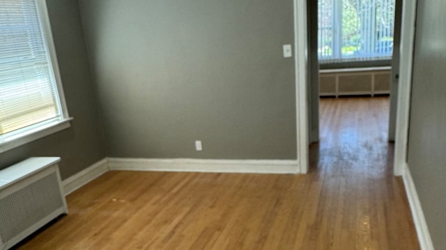 spare room featuring radiator heating unit and light hardwood / wood-style flooring