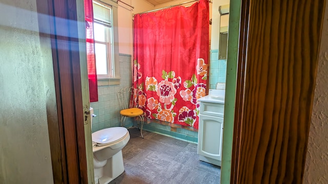 bathroom featuring tile floors, vanity, toilet, and tile walls