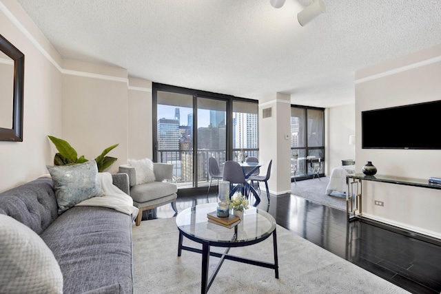 living room featuring crown molding, hardwood / wood-style floors, a textured ceiling, and a wall of windows