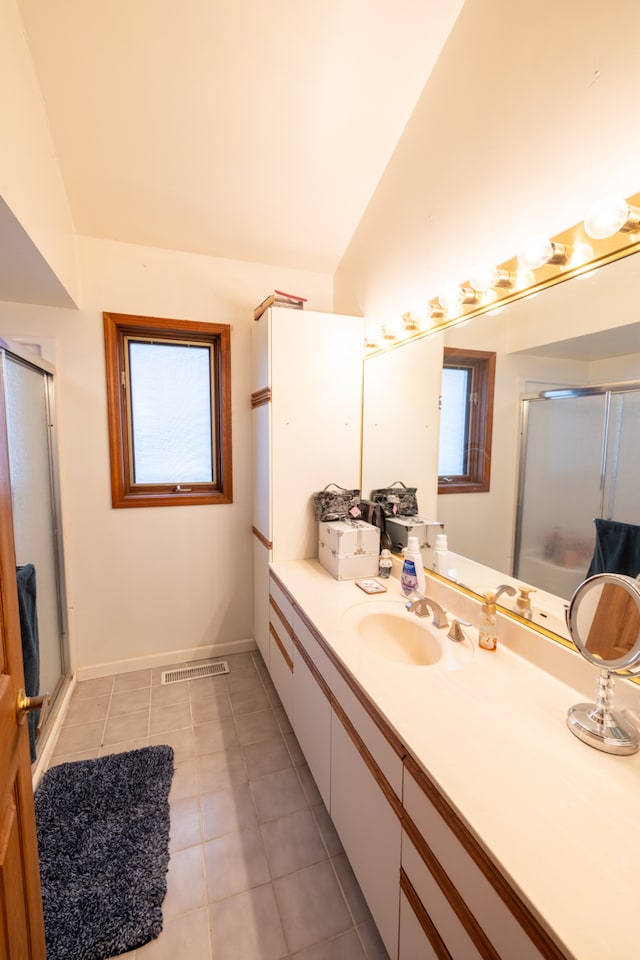 bathroom featuring tile floors, vanity, vaulted ceiling, and a shower with door